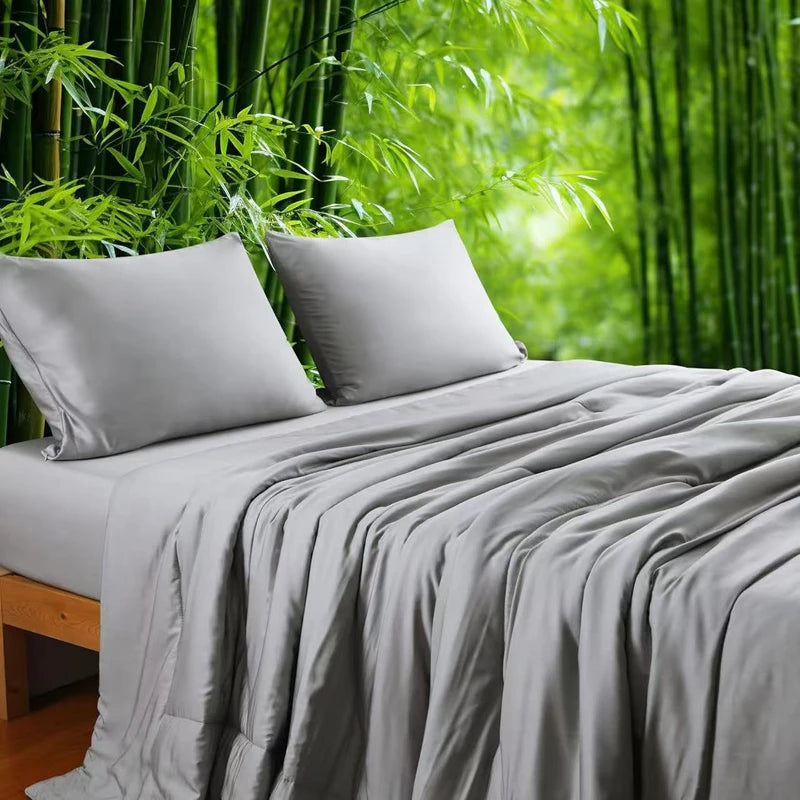  Silver Grey 100% bamboo fibre cooling quilt draped over a bed with matching pillowcases against a lush bamboo forest backdrop, showing the smooth, lightweight fabric in a soft grey tone