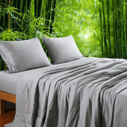  Silver Grey 100% bamboo fibre cooling quilt draped over a bed with matching pillowcases against a lush bamboo forest backdrop, showing the smooth, lightweight fabric in a soft grey tone
