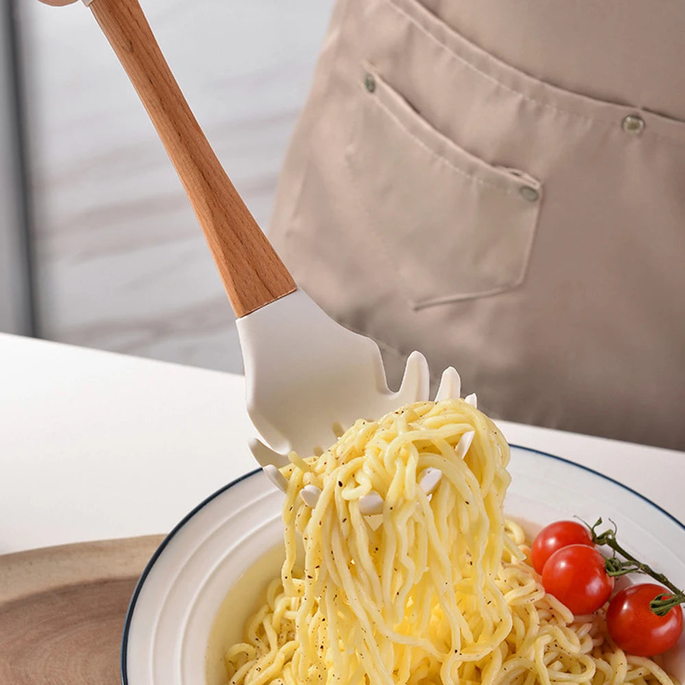 Person in linen apron using white silicone pasta server with bamboo handle to serve spaghetti into a bowl with cherry tomatoes, CL House & Home