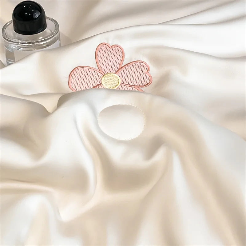 "Close-up of Ice Bloom cooling summer quilt in Blossom Pink — silky smooth ice silk fabric with detailed pink daisy embroidery and gold centre, lightweight and breathable"

