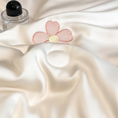 "Close-up of Ice Bloom cooling summer quilt in Blossom Pink — silky smooth ice silk fabric with detailed pink daisy embroidery and gold centre, lightweight and breathable"

