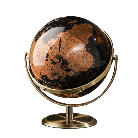 Decorative world globe with black and gold vintage map on gold-plated stand, styled on a dark glass desk with notebook and pen in a moody home office setting