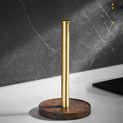 Walnut & Gold Paper Towel Holder without roll on a white countertop — brushed gold rod and round walnut wood base, dark marble wall background.