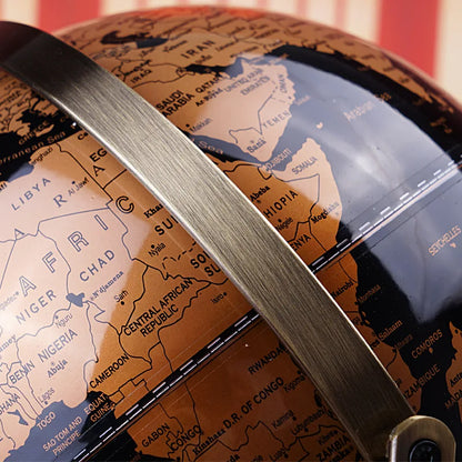 Close-up of decorative world globe surface showing black and gold vintage map detail with brushed gold metal ring frame, Africa and Middle East regions visible