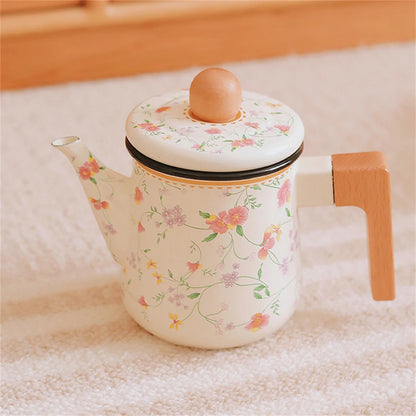 Floral enamel teapot with wooden handle placed on a soft linen surface, full view showing pink and lilac blossom print and elegant spout — Blossom Kettle by CL House