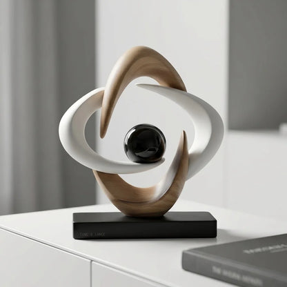 White and gold abstract resin sculpture with a glossy black sphere on a black base, styled on a white sideboard beside a book.