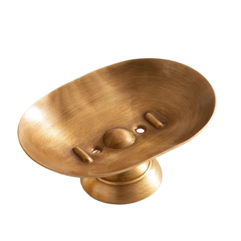 Antique brass oval soap dish on pedestal base with drainage holes, brushed warm gold finish, white background