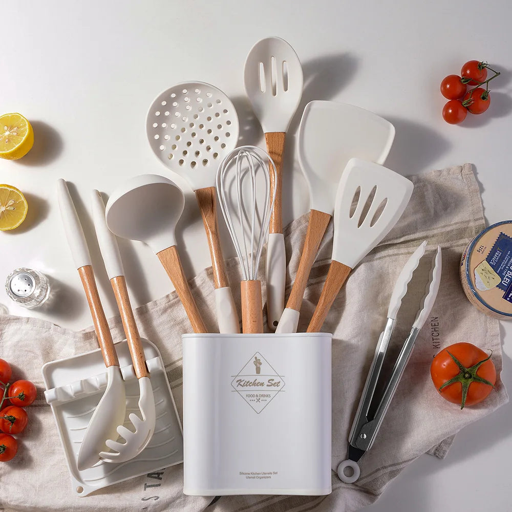 White silicone kitchen utensils set with bamboo handles displayed in storage holder on linen cloth styled with tomatoes, lemon and cheese, CL House & Home