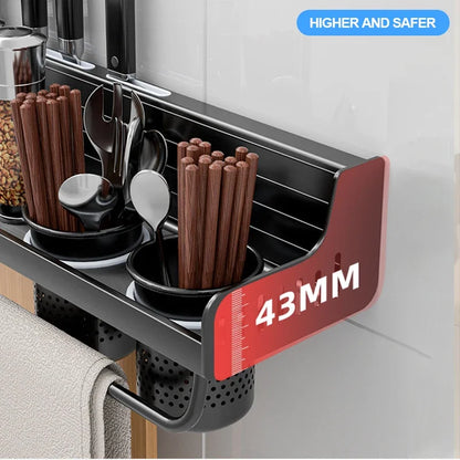 Close-up detail of matte black kitchen shelf side panel showing 43mm raised edge height for secure storage — two organiser cups with chopsticks and cutlery on the shelf, towel bar below, "Higher and Safer" safety feature highlighted