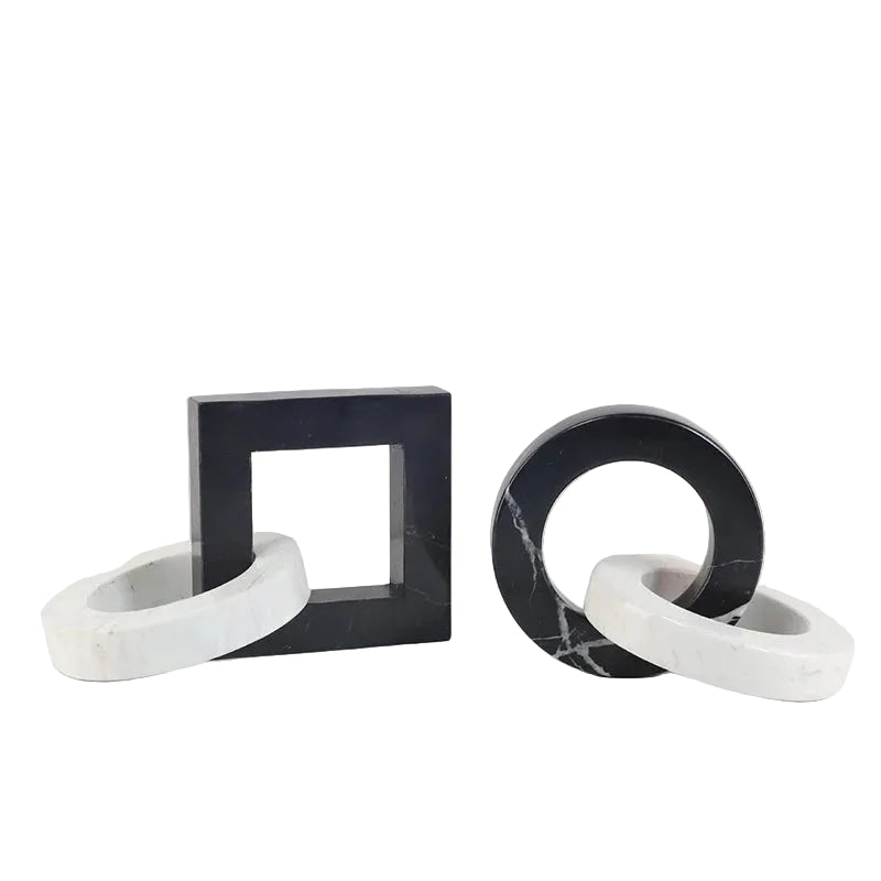 Round and square black and white interlocking marble sculptures styled together on a book and a neutral surface