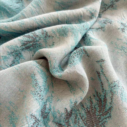 Close-up of the Teal Garden bamboo fibre jacquard blanket fabric showing the detailed botanical fern weave pattern in soft teal and sage tones with a smooth silky texture