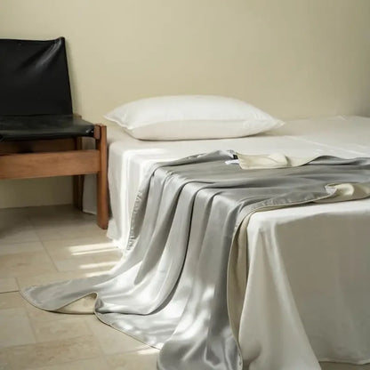 Pearl Silver 100% Tencel cooling summer blanket draped over a bed in a minimalist bedroom