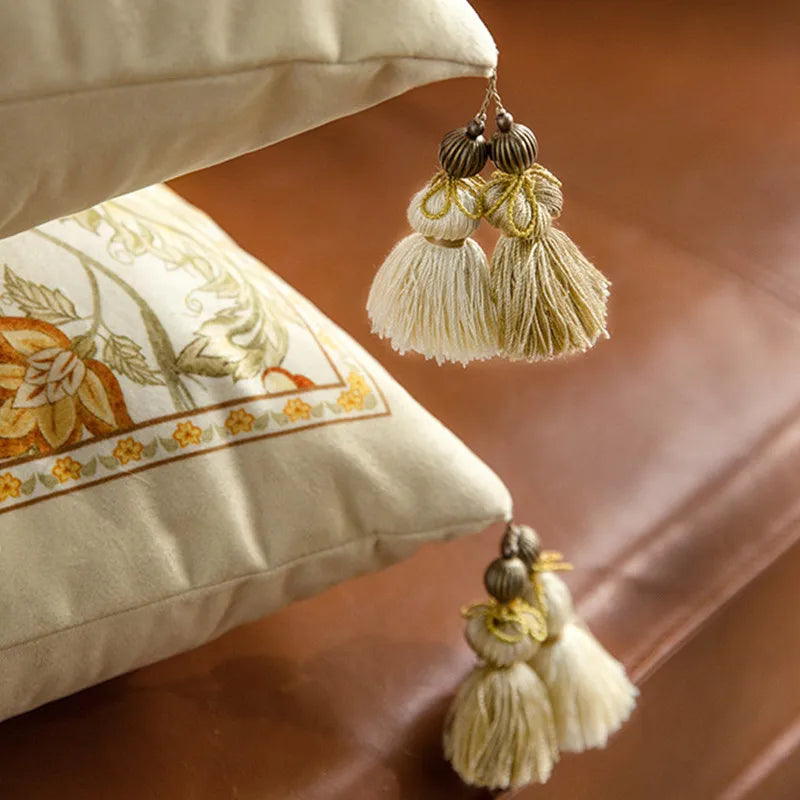  "Golden Frame" and "Wild Harvest" floral embroidered cushion covers styled on a brown leather sofa with gold velvet cushions, amber botanical motifs on ivory velvet — CL House Cushions collection