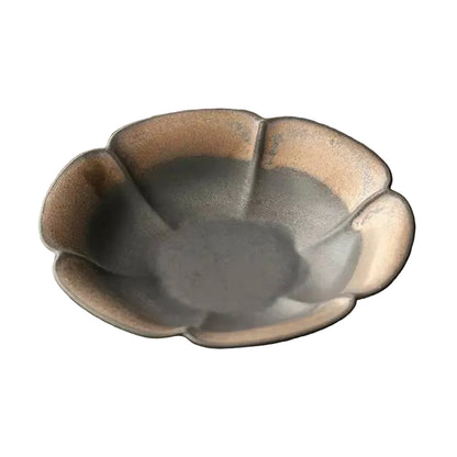 Charcoal petal ceramic dish close-up showing dark matte glaze with bronze rim highlights, white background