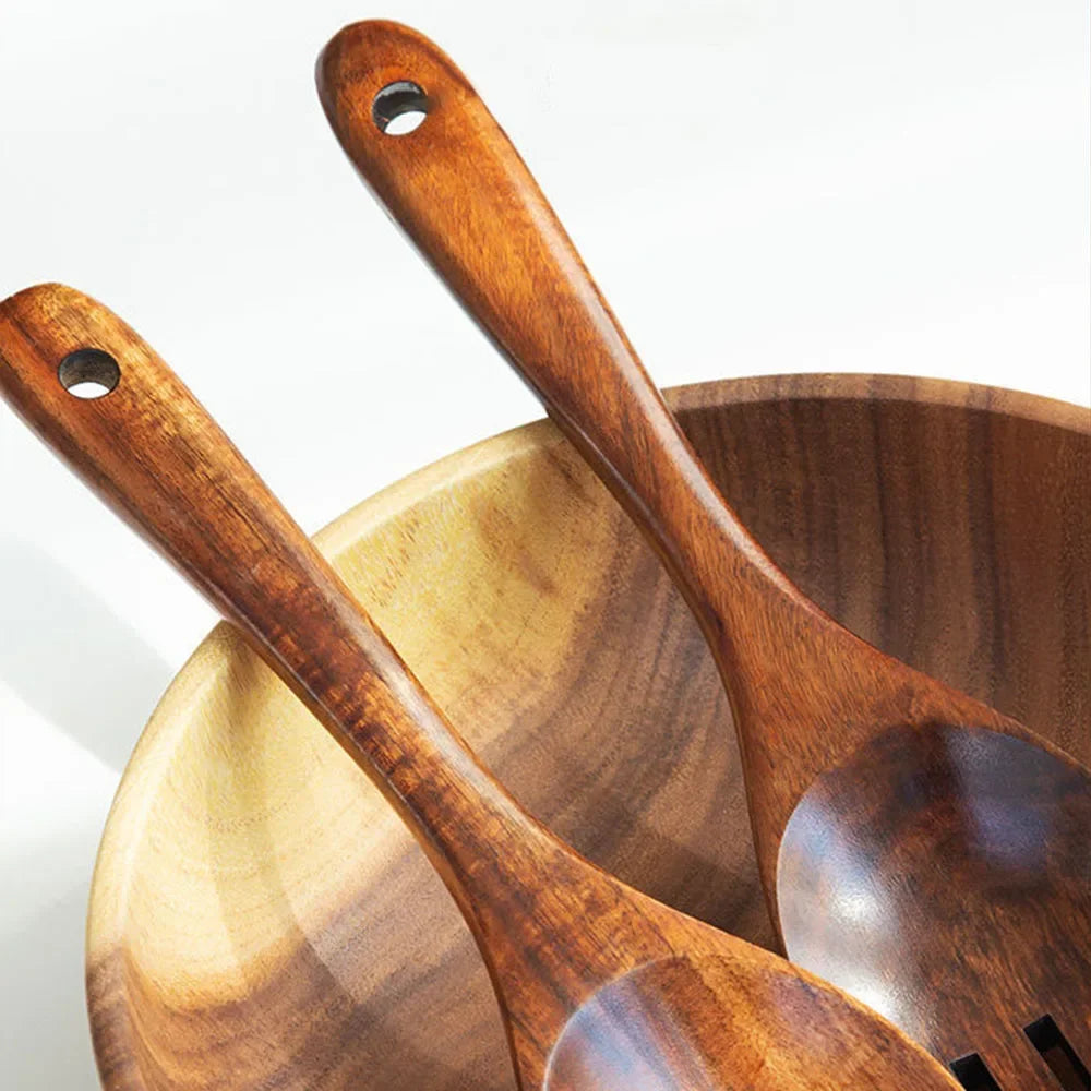 "Wild Harvest" acacia wood salad servers resting in a wooden bowl, close-up detail of natural wood grain and long handles