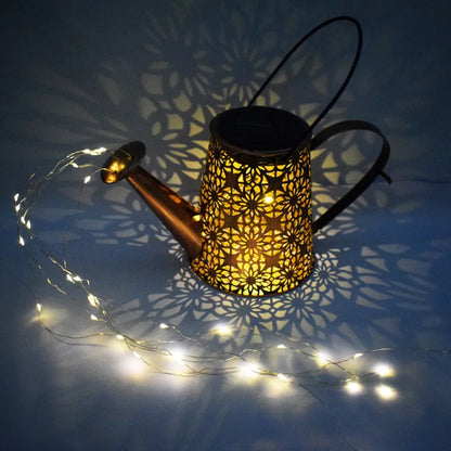Starfall Kettle" solar fairy light watering can, Bloom Copper finish with floral cutout pattern, illuminated at night casting intricate mandala shadow projection on surface, warm LED fairy lights trailing from spout, no pole version