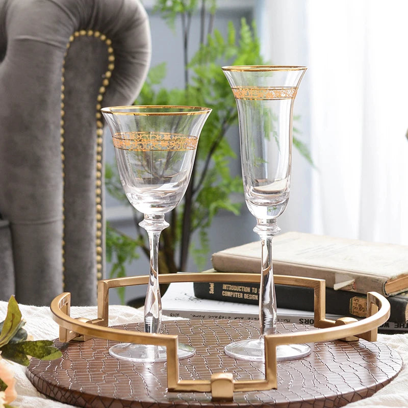 "Golden Filigree" crystal wine glass and champagne flute side by side on white background, showing gold rim and engraved band detail