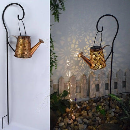 "Starfall Kettle" solar fairy light watering can, Bloom Copper finish with floral cutout pattern, mounted on black shepherd's hook pole, warm LED fairy lights cascading from spout — shown by day and illuminated at night with mandala shadow projection on wall, garden setting