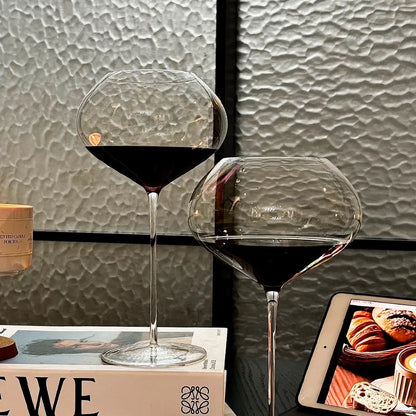  "Gravity" disc bowl crystal wine glass filled with wine in a cosy setting with books, distinctive flat disc bowl and elegant stem — CL House Drinkware collection