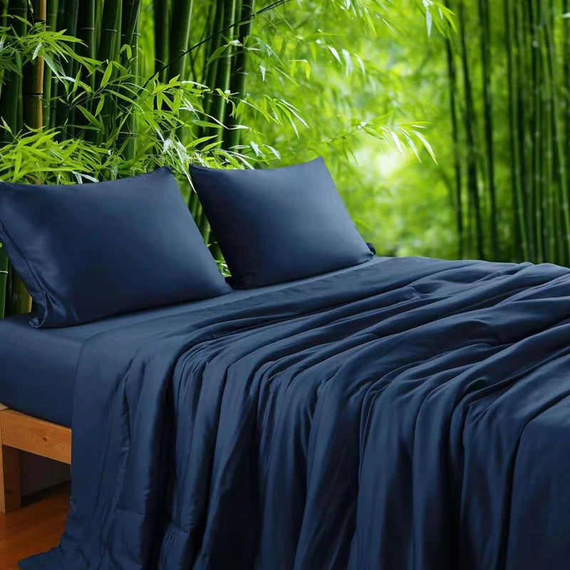  Midnight Blue 100% bamboo fibre cooling quilt draped over a bed with matching pillowcases against a lush bamboo forest backdrop, showing the smooth, lightweight fabric in a deep navy blue tone