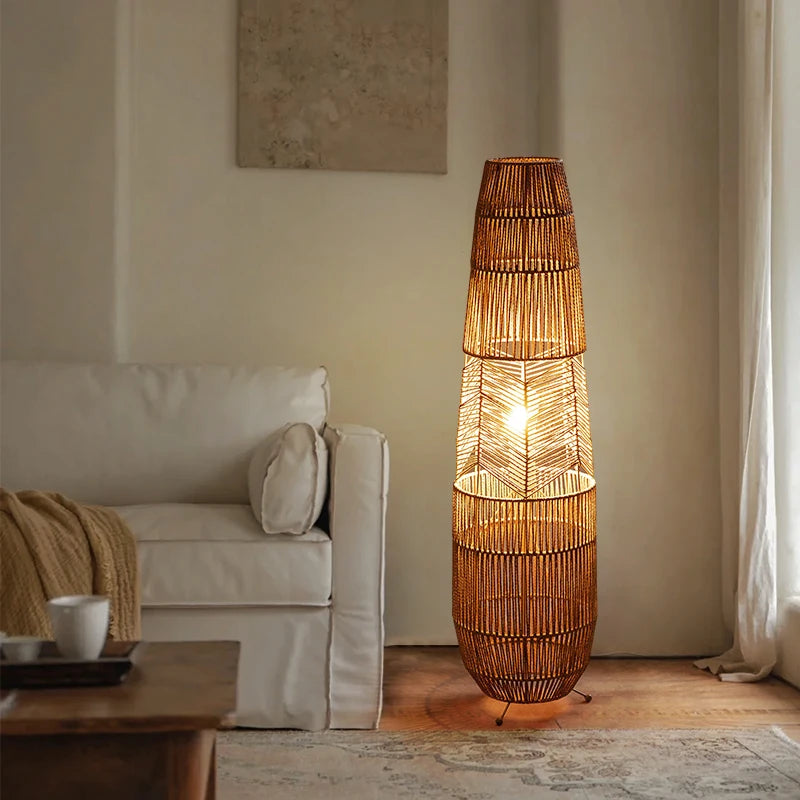  "Weave & Glow" rattan floor lamp with herringbone weave detail glowing warmly in a neutral living room corner beside a white sofa and sheer curtains
