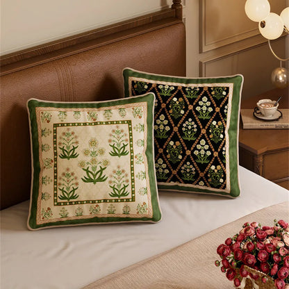 "Ivory Garden" and "Midnight Trellis" Indo-Persian velvet cushion covers styled on a leather bed — ivory ground with green botanical block print paired with black ground diamond trellis and white florals, sage green reverse with cream piping — CL House