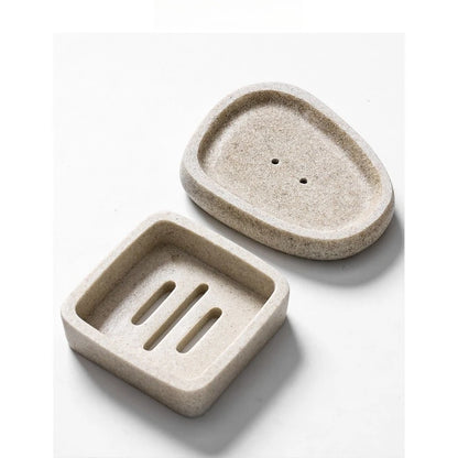 Square and pebble stone-texture resin soap dishes in sand beige displayed together, showing drainage slots and drainage holes, minimalist bathroom accessory set