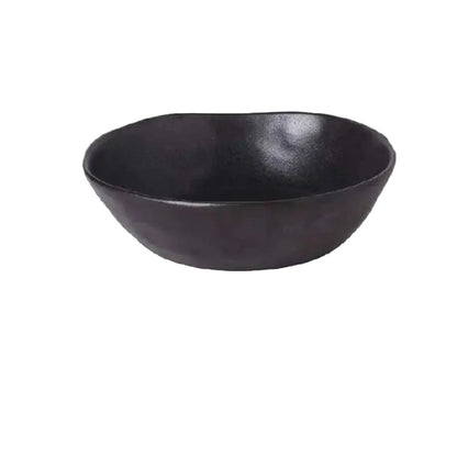 "Speckled Stone" ceramic serving bowl in matte black with organic irregular rim — front view on white background