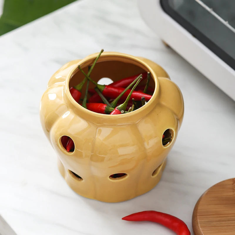 Mustard yellow pumpkin-shaped ceramic jar open without lid filled with fresh red chillies on a marble surface, CL House & Home