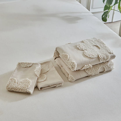 Folded "Daisy Field" tufted duvet cover and two pillowcases set displayed on a white bed — ivory sand cotton bedding set with raised daisy flower detail