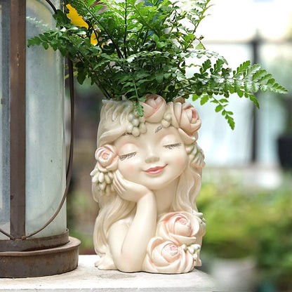 "Rose Muse" resin fairy head planter in Blush Cream — styled with fern beside a vintage lantern on an outdoor terrace