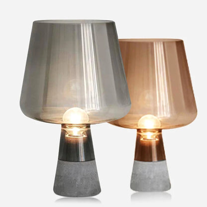 Pair of illuminated table lamps with translucent grey and amber glass shades, glossy metallic necks and textured grey bases, displayed against a white background.
