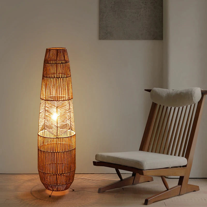  "Weave & Glow" rattan floor lamp glowing warmly beside a wooden lounge chair against a clean white wall