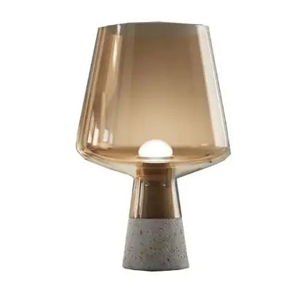 "Smoke & Cement" glass table lamp with amber shade and exposed bulb on a raw cement base, white background