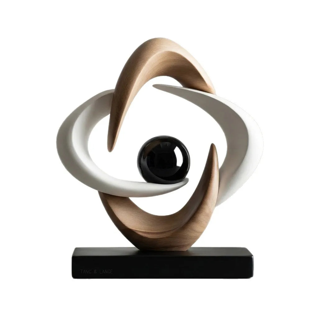 White and gold abstract resin sculpture with interlocking curved loops and a glossy black sphere on a black rectangular base, shown against a white background.