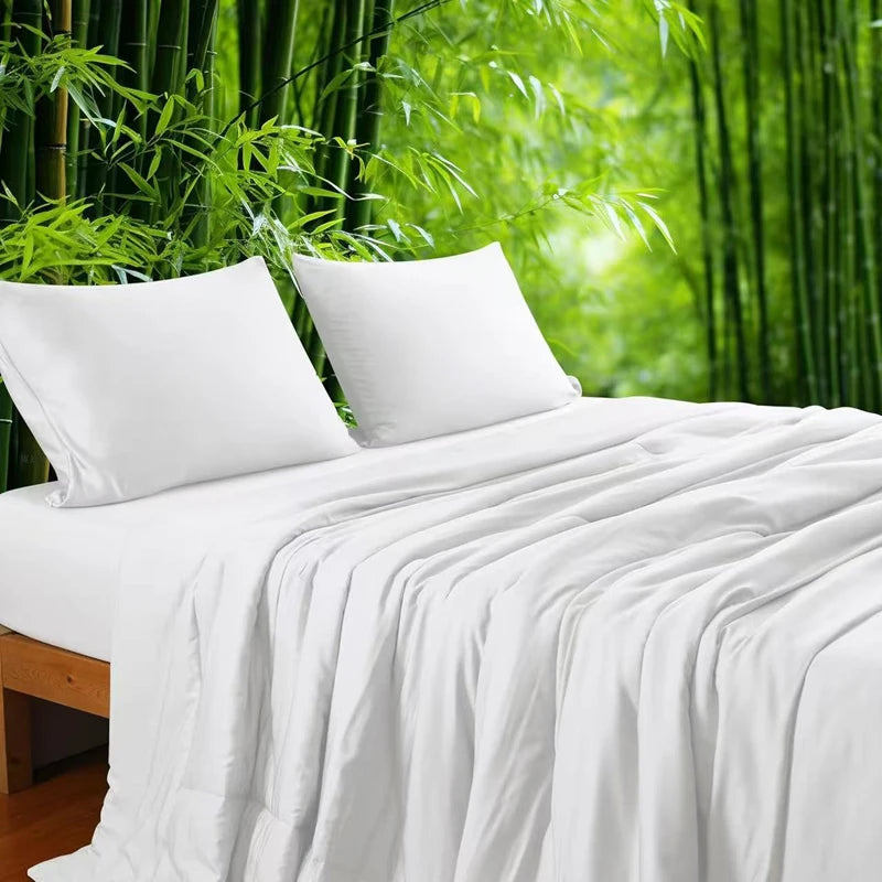 Ivory White 100% bamboo fibre cooling quilt draped over a bed with matching pillowcases against a lush bamboo forest backdrop, showing the smooth, lightweight fabric in a clean crisp white tone