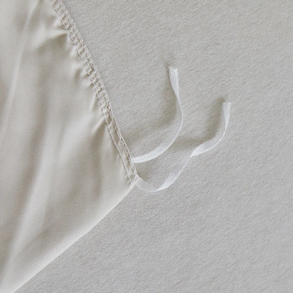 Interior corner ties detail of "Daisy Field" duvet cover to keep the duvet insert securely in place — quality overlock stitching on ivory cotton fabric