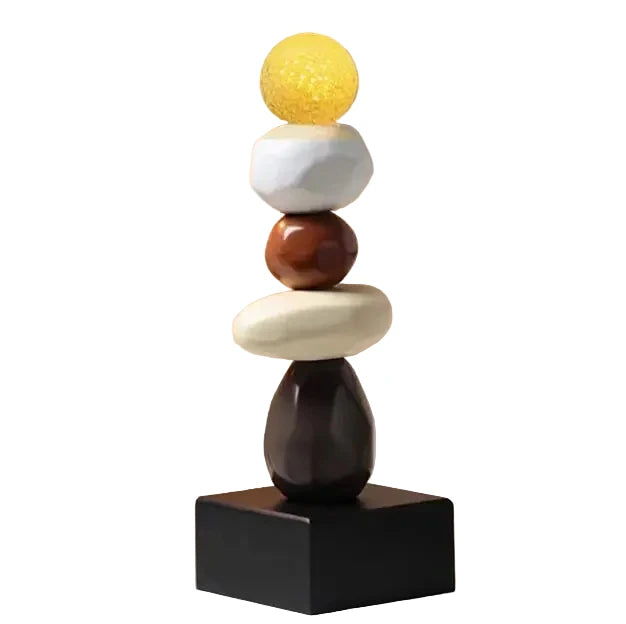 Abstract ceramic stacked sculpture with a yellow upper sphere, white and brown rounded forms, a cream oval element and a black square base, displayed against a white background.