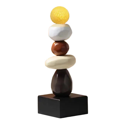 Abstract ceramic stacked sculpture with a yellow upper sphere, white and brown rounded forms, a cream oval element and a black square base, displayed against a white background.