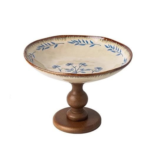 "Blue Botanics" ceramic pedestal serving stand with hand-painted blue freesia and leaf motif, on a solid walnut wood turned base — white background