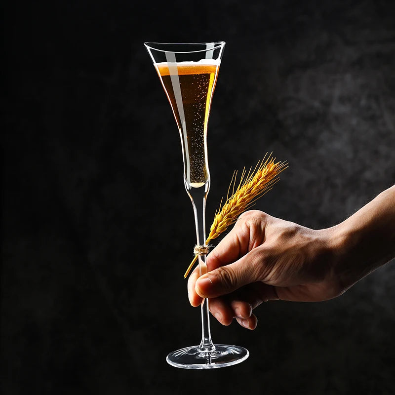  Hand holding a "Trumpet" crystal champagne flute, elegant elongated silhouette — CL House Drinkware collection