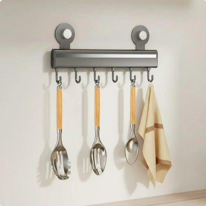 Gray adhesive wall-mounted kitchen hook rail with seven sliding hooks holding bamboo handle utensils and a linen kitchen towel, CL House & Home