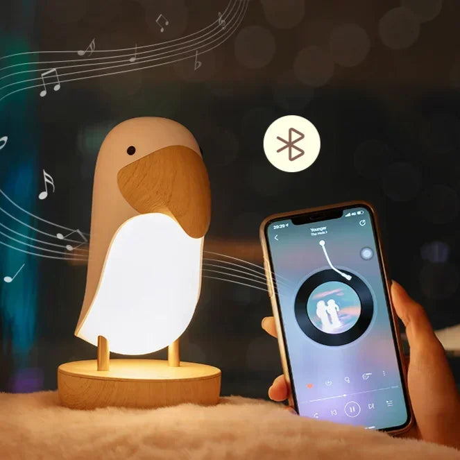 Pink Birdie LED night light glowing next to a smartphone playing music, with Bluetooth icon and music notes illustrating wireless speaker pairing