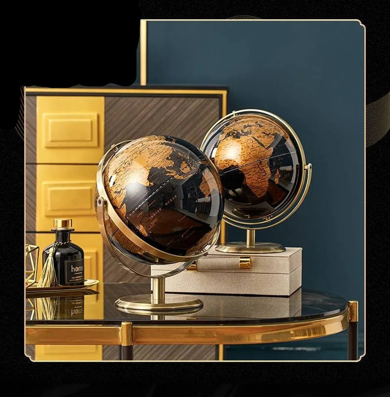 Two decorative world globes with black and gold vintage map on gold-plated stands, styled on a dark console table in a luxury blue and gold interior