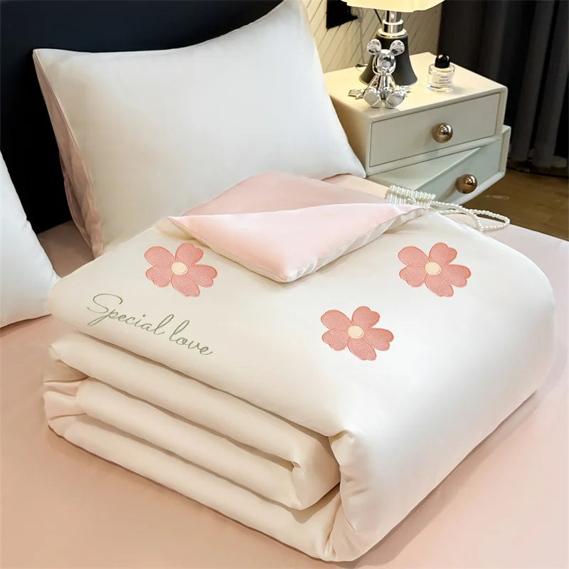 "Ice Bloom cooling summer quilt in Blossom Pink — ivory white with embroidered pink daisy motifs and 'Special Love' script detail, blush pink reverse"