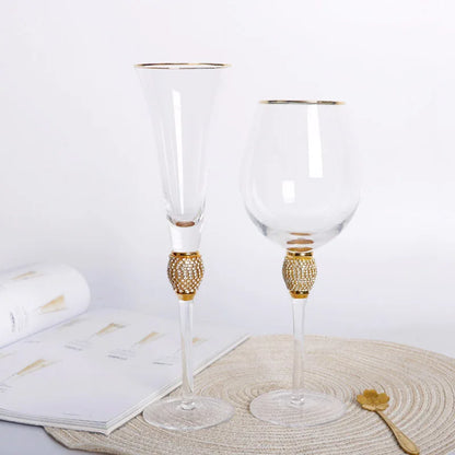 "Golden Jewel" Champagne Flute and Wine Glass with gold rim and micro-crystal bead stems, styled on a woven placemat with a white book and gold spoon