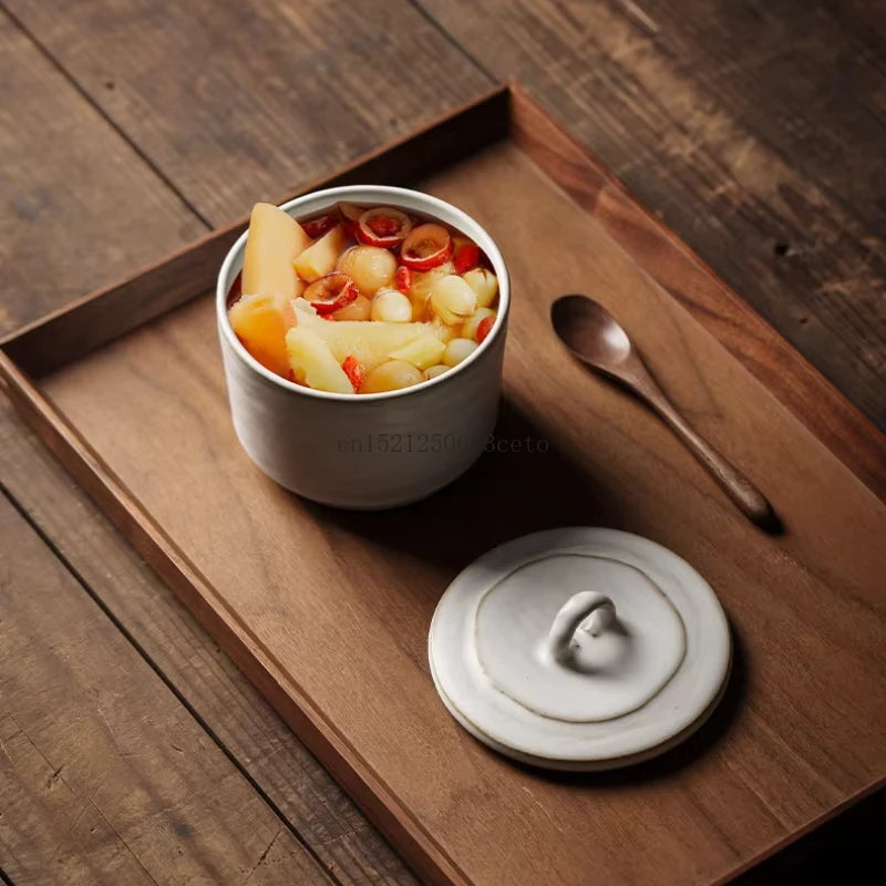 Ceramic lidded bowl filled with a colourful fruit dessert soup — melon, longan and red dates — lid set aside on a dark walnut wooden tray with a wooden spoon, lifestyle setting