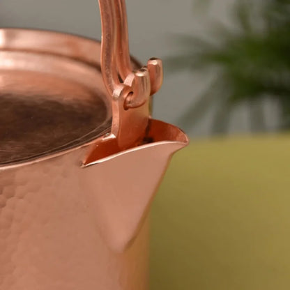 Copper Ritual close-up detail of the hand-hammered copper spout and handle hinge joint in Rose Gold finish, showing the precision of the artisan craftsmanship against a soft green background