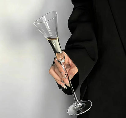 Hand holding a "Trumpet" crystal champagne flute filled with champagne, elegant trumpet-shaped silhouette — CL House Drinkware collection
