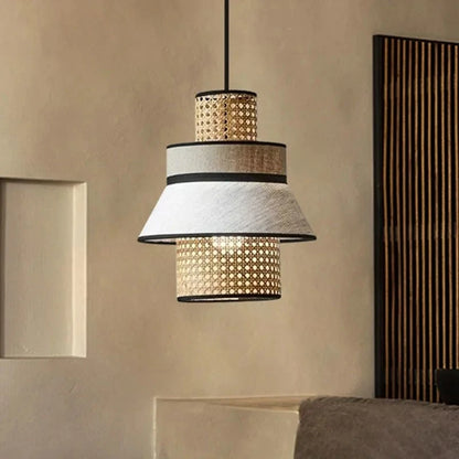 "Layer & Loom" tiered rattan and linen pendant light against a textured neutral wall with dark wood slat panel, japandi interior styling